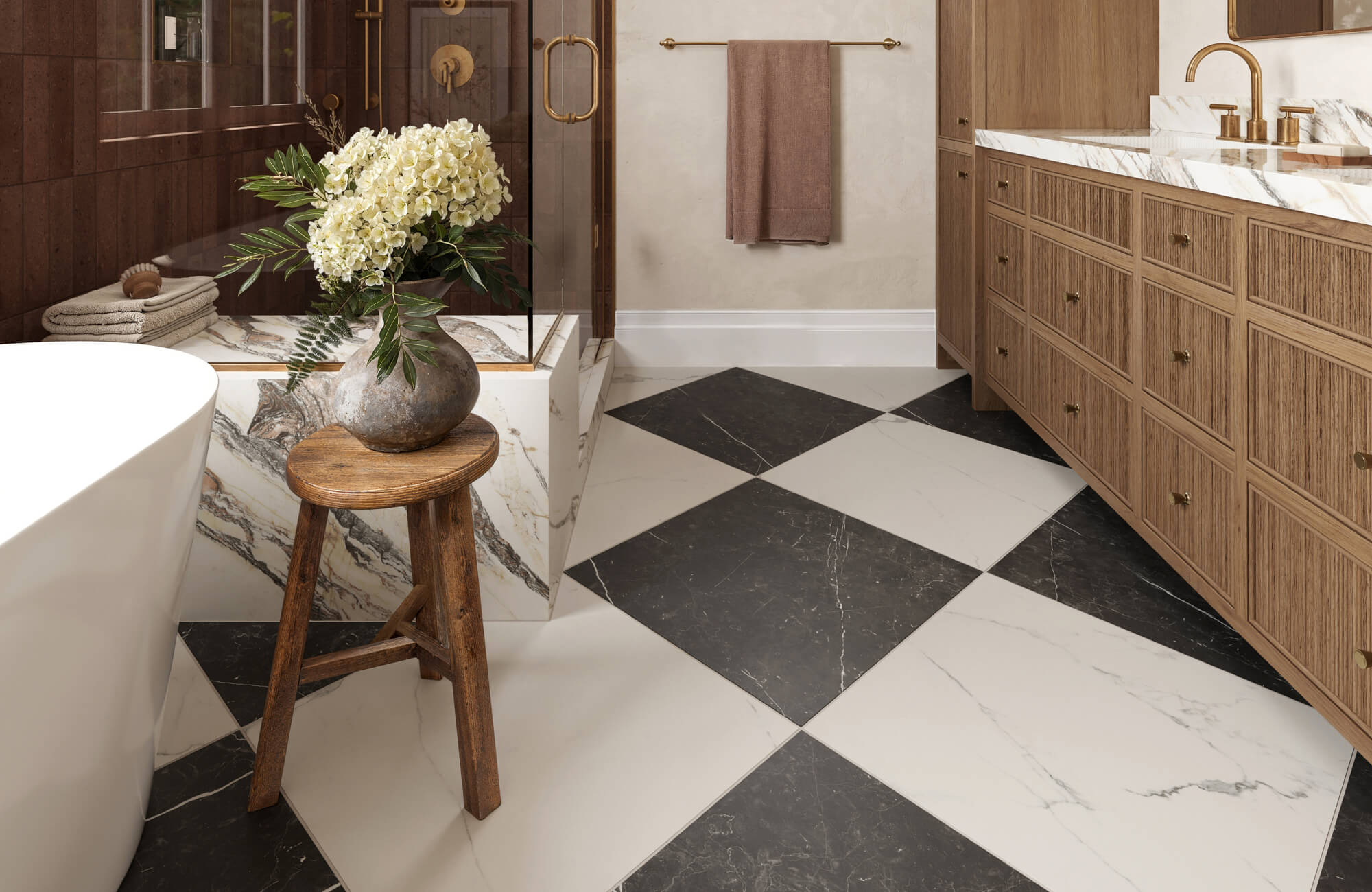 null Traditional bathroom with 24x24 black and white checkerboard floor tile, a wood double vanity, marble-look countertops, brass fixtures, a freestanding tub, a glass shower with dark wall tile, and a wooden stool with flowers.