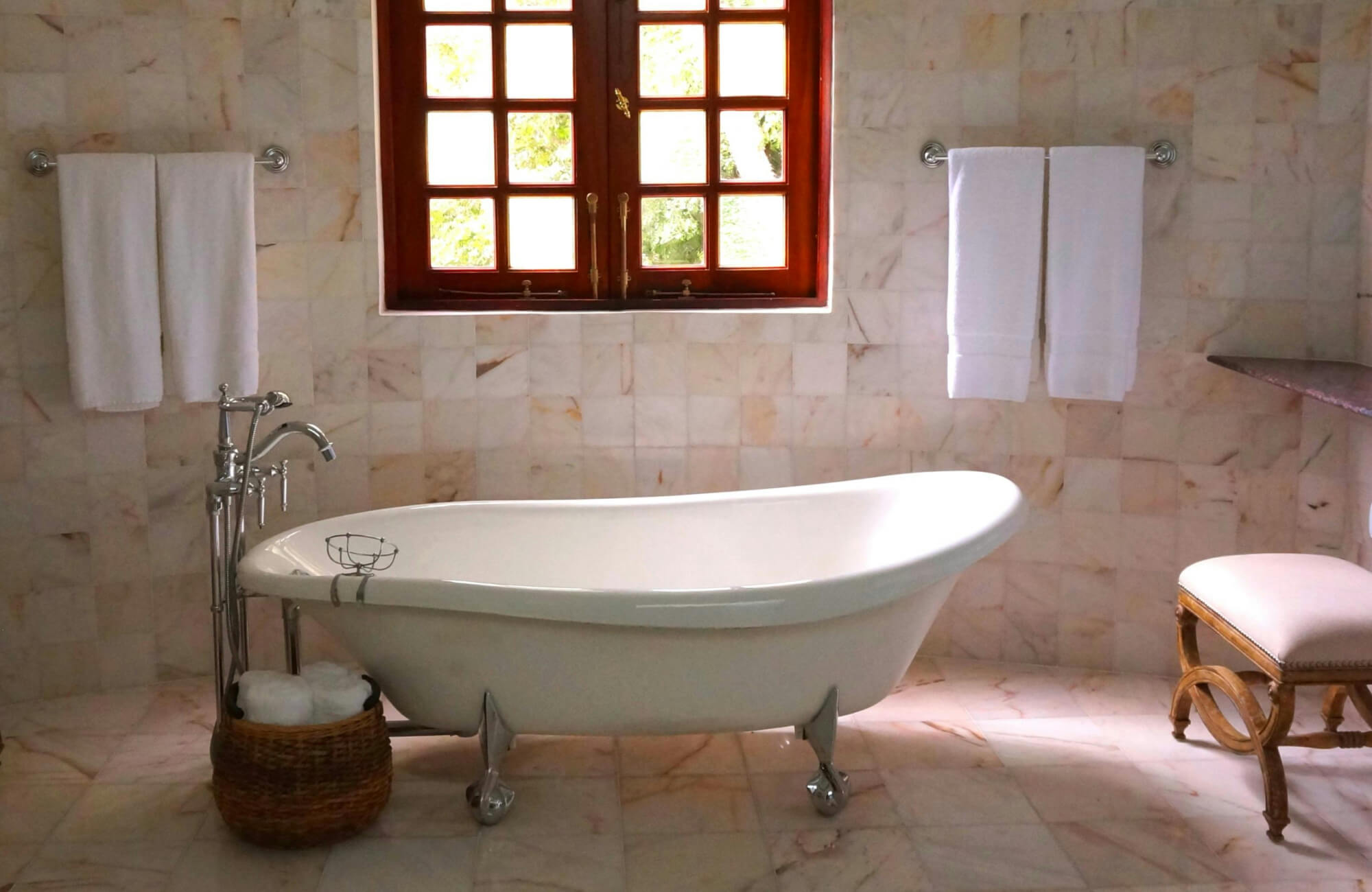 Elegant bathroom with a glass-enclosed shower and built-in bathtub, featuring beige floor and wall tiles with a decorative mosaic border for a refined touch.