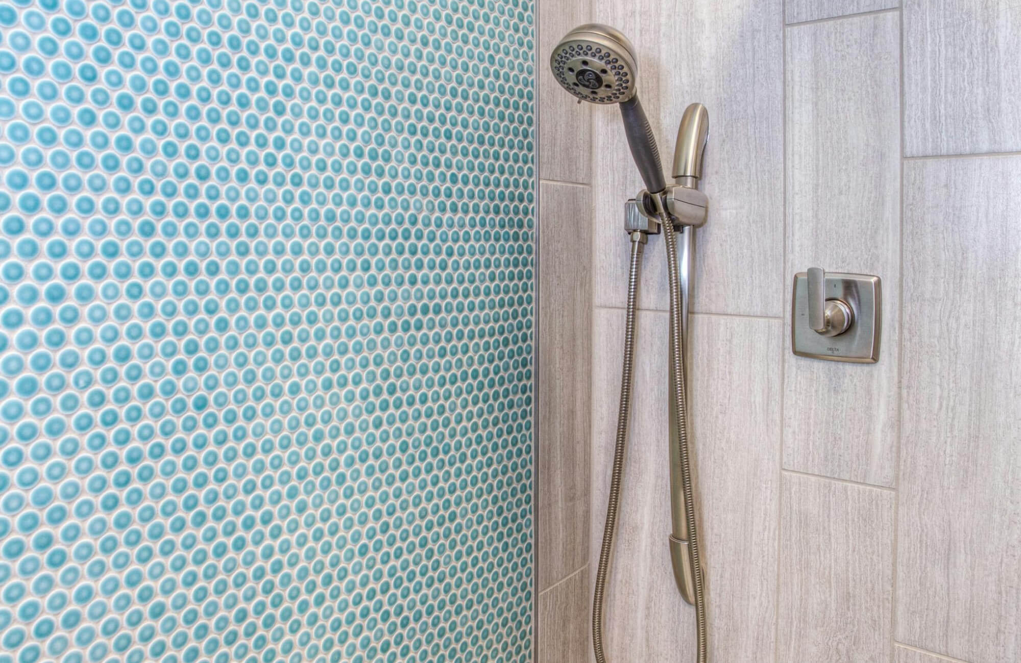 Contemporary shower with vibrant blue penny tile accent wall and wood look porcelain tiles, complemented by a sleek brushed nickel showerhead.