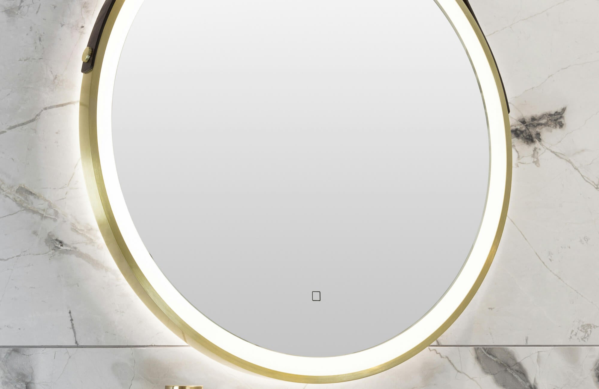 null Round backlit mirror with a brushed brass frame set against elegant white marble tiles with soft grey veining.