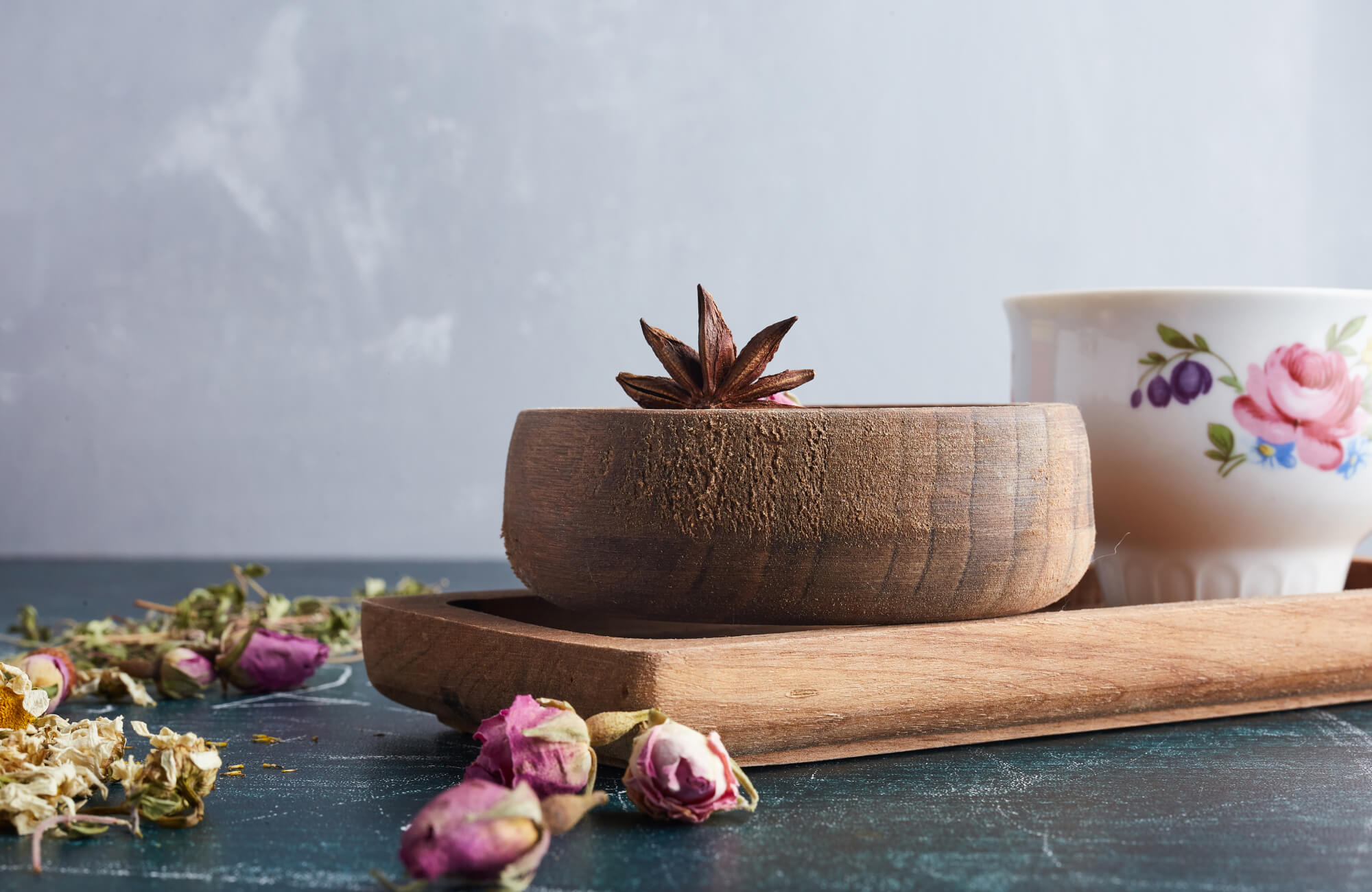 Showcasing rich wood grain and a hand-crafted look, this decorative bowl serves as a simple tabletop accent alongside dried botanicals, spices, and vintage-inspired pieces.