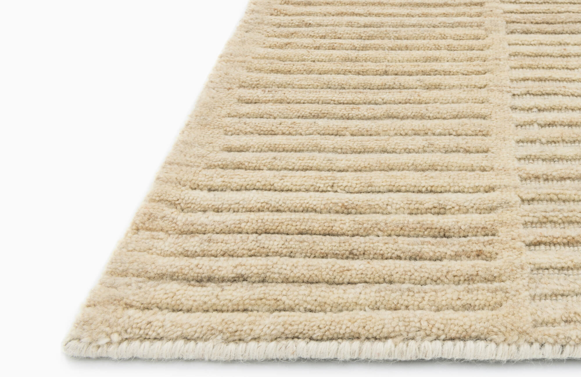 Close-up of beige wool rug with raised linear texture, looped pile rows, and neatly finished edge on a clean white background.