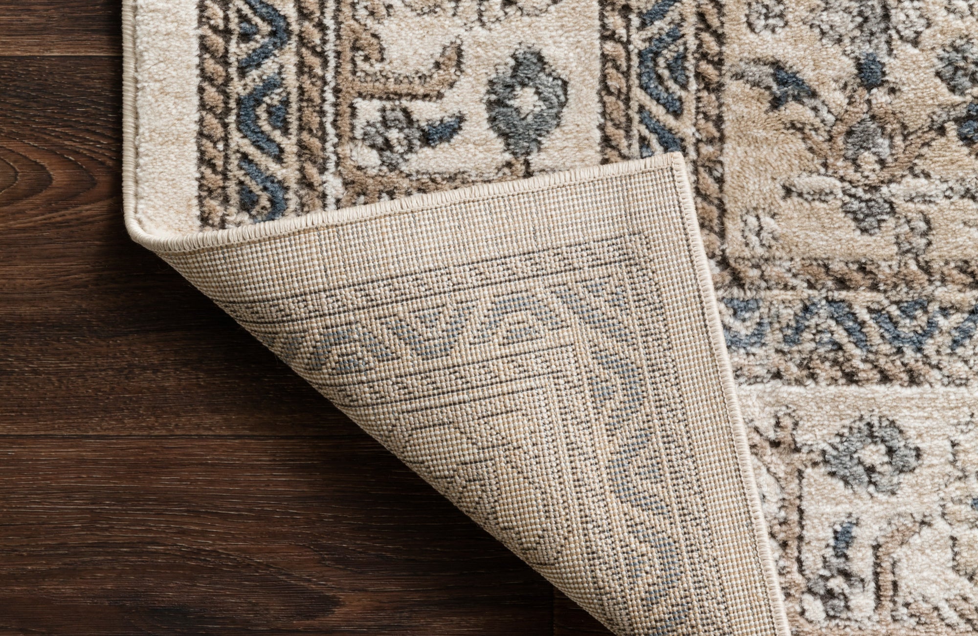 Close-up of woven polypropylene outdoor rug corner with intricate patterns and sturdy, weather-resistant backing.