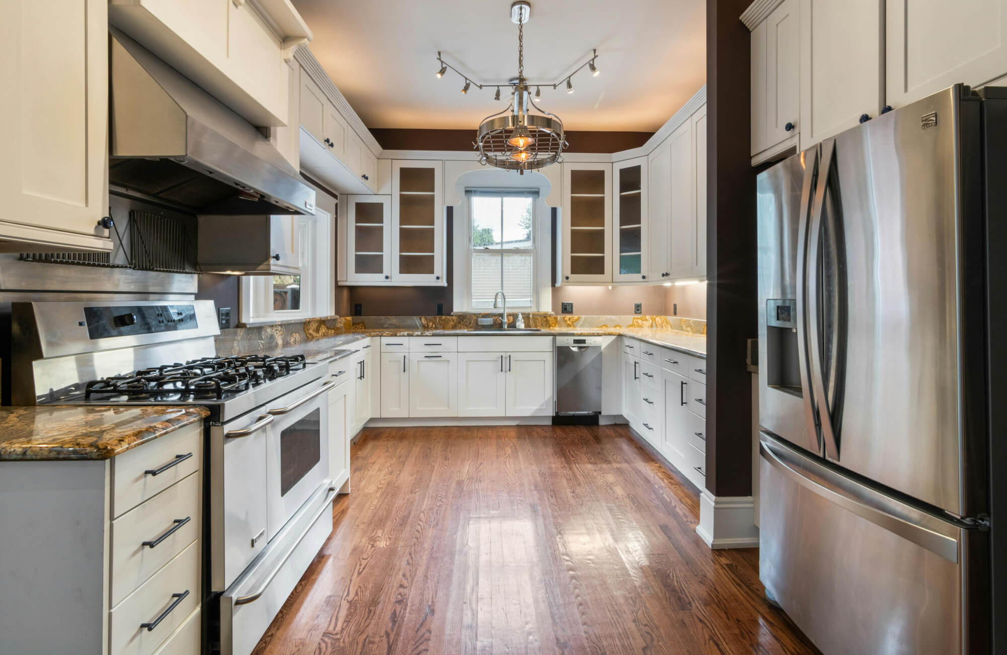 null Classic kitchen interior featuring polished hardwood floors, white cabinetry, stainless steel appliances, and granite countertops.