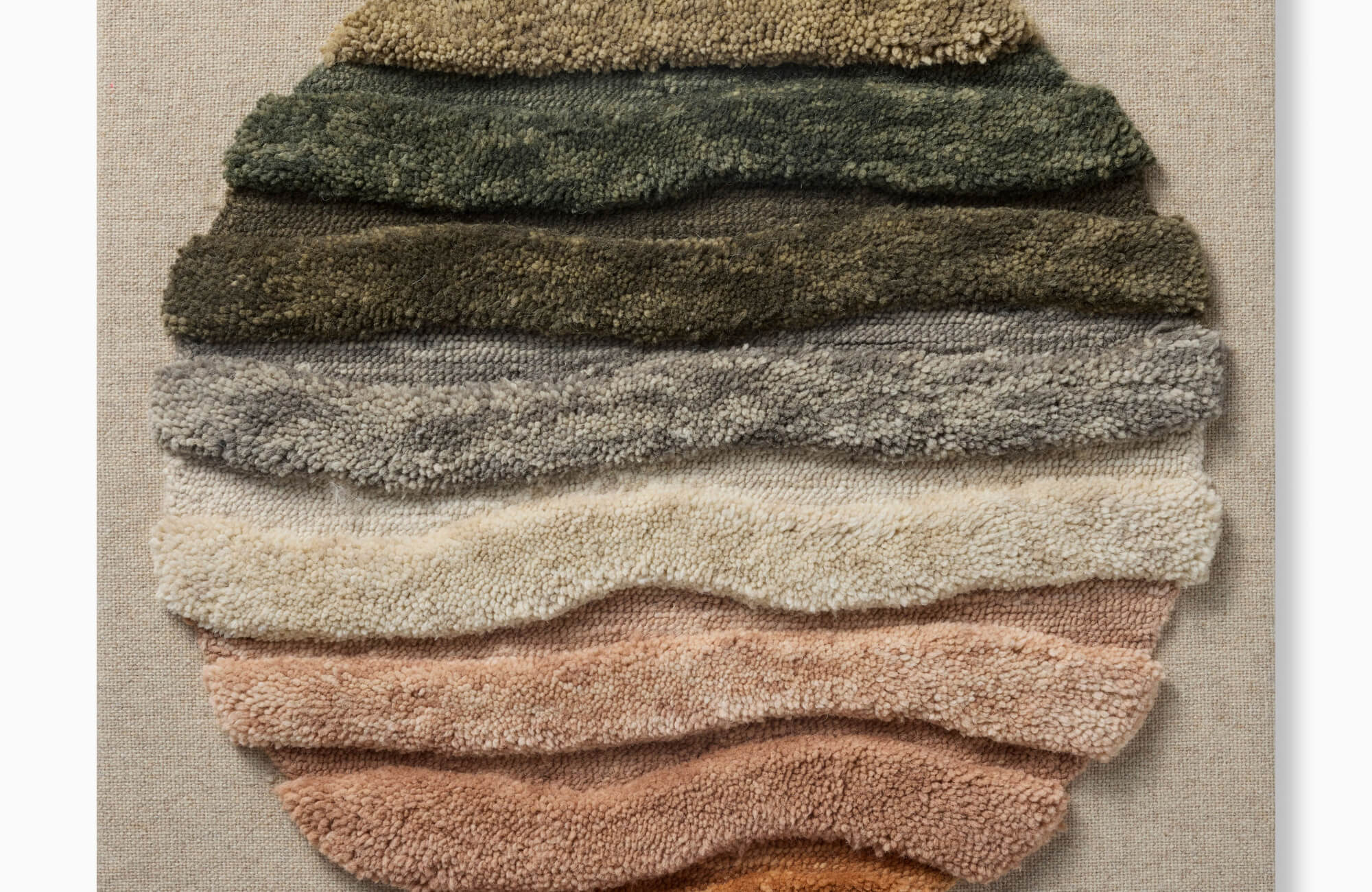null Textured circular wall art with layered neutral tones in green, beige, and rust on fabric backing, creating a soft sculptural effect.