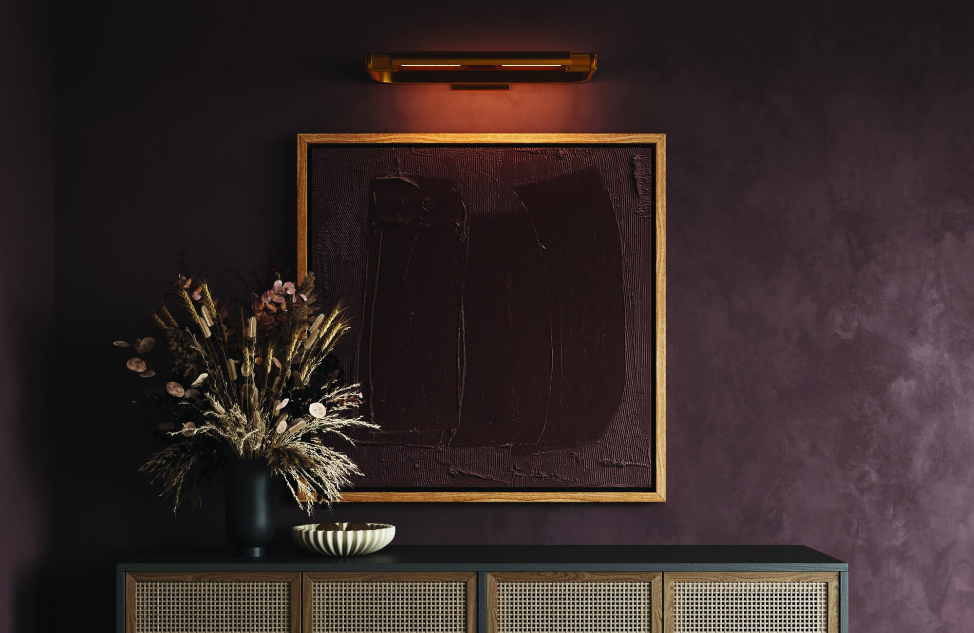 A refined linear wall light with a warm metallic finish illuminates framed artwork, casting a soft focused glow that enhances the moody wall texture and creates an elegant, gallery-inspired atmosphere.