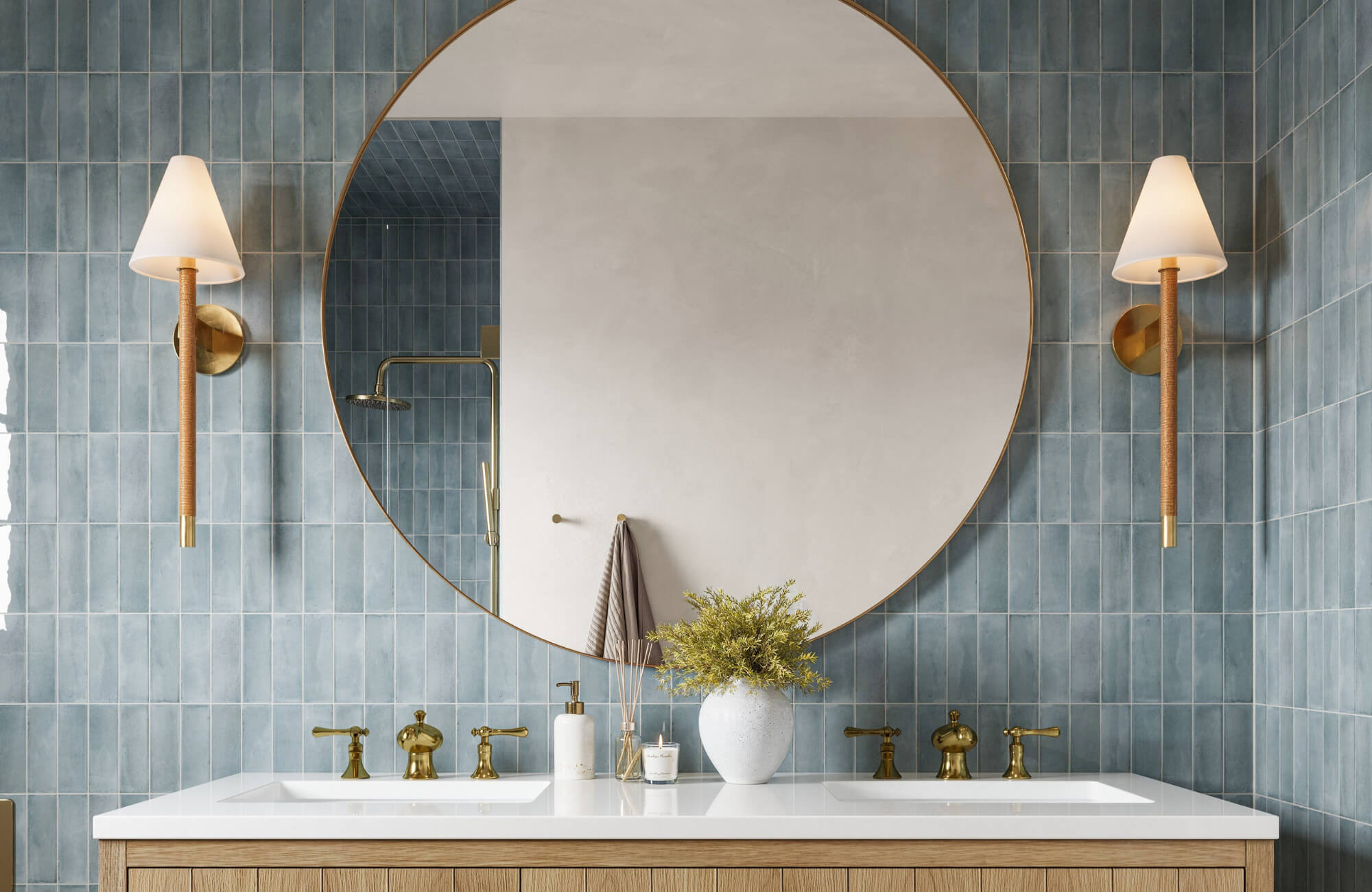 null Bathroom with a large round mirror, brass fixtures, double sink vanity, blue vertical tile walls, and modern wall sconces on each side.