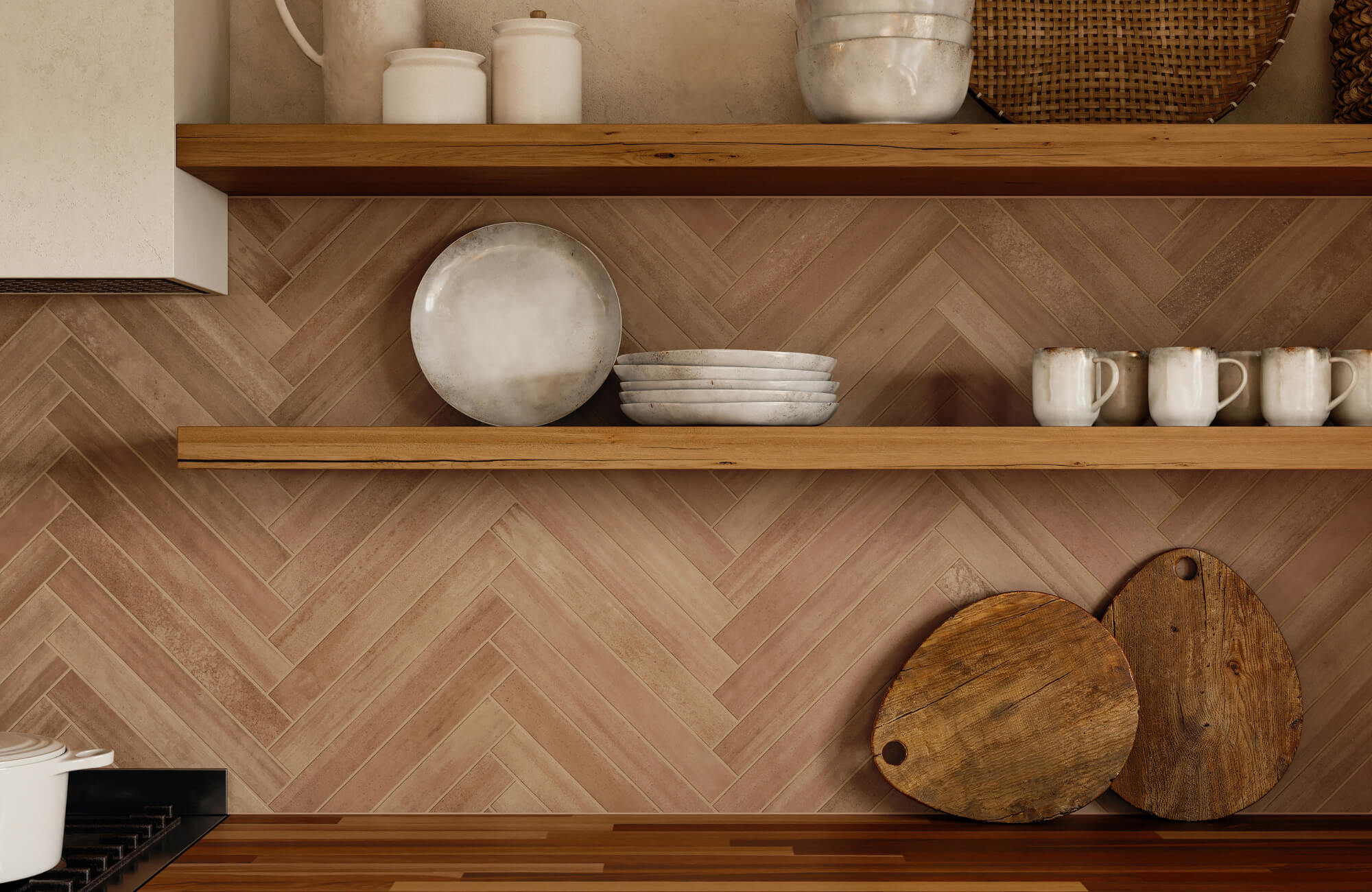 Close-up of a kitchen backsplash with herringbone-patterned brown tiles, wooden shelves holding ceramics, mugs, and rustic cutting boards.