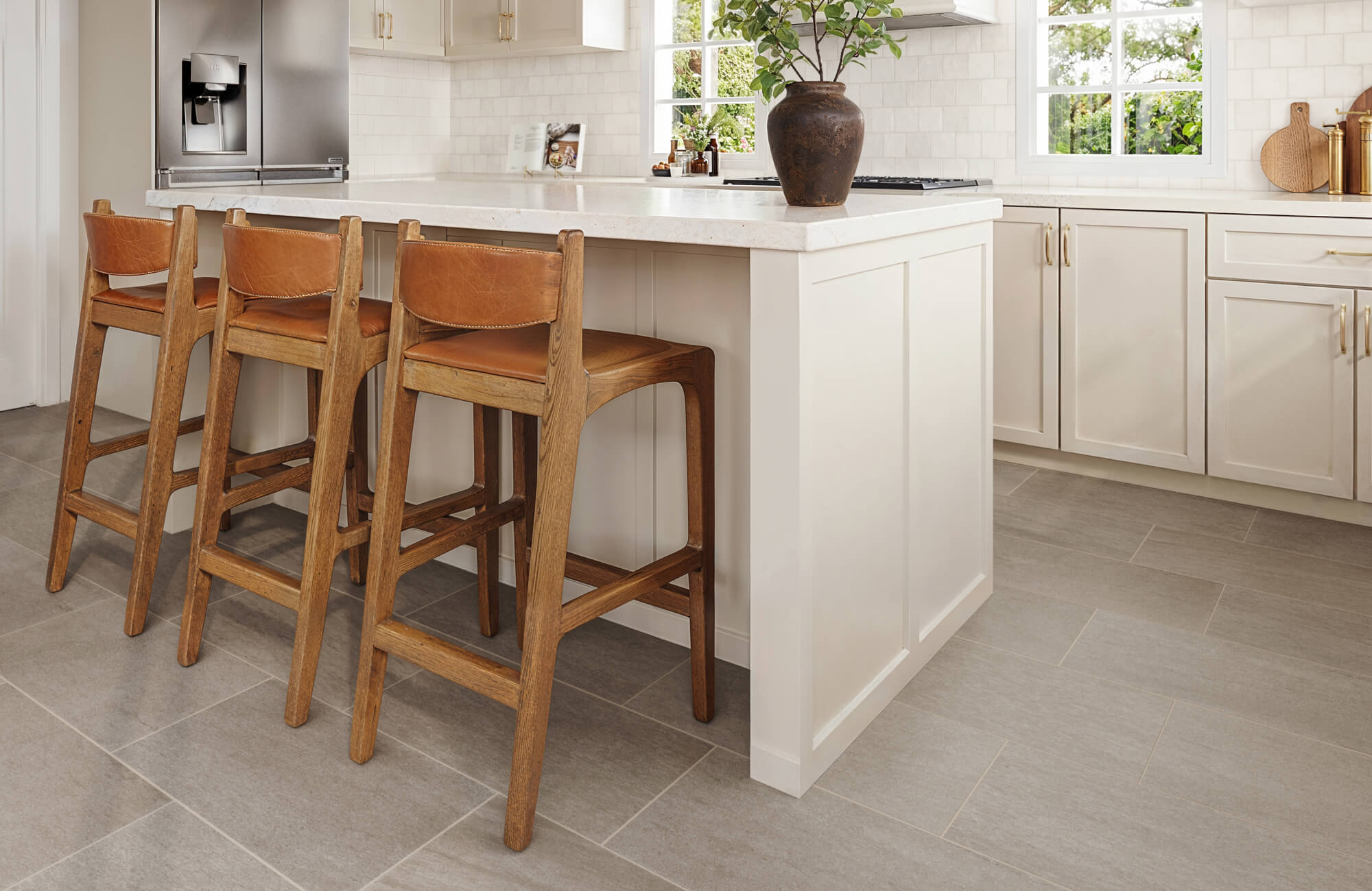 null Modern kitchen with large-format stone-look tiles in gray, paired with a white island and wooden bar stools.