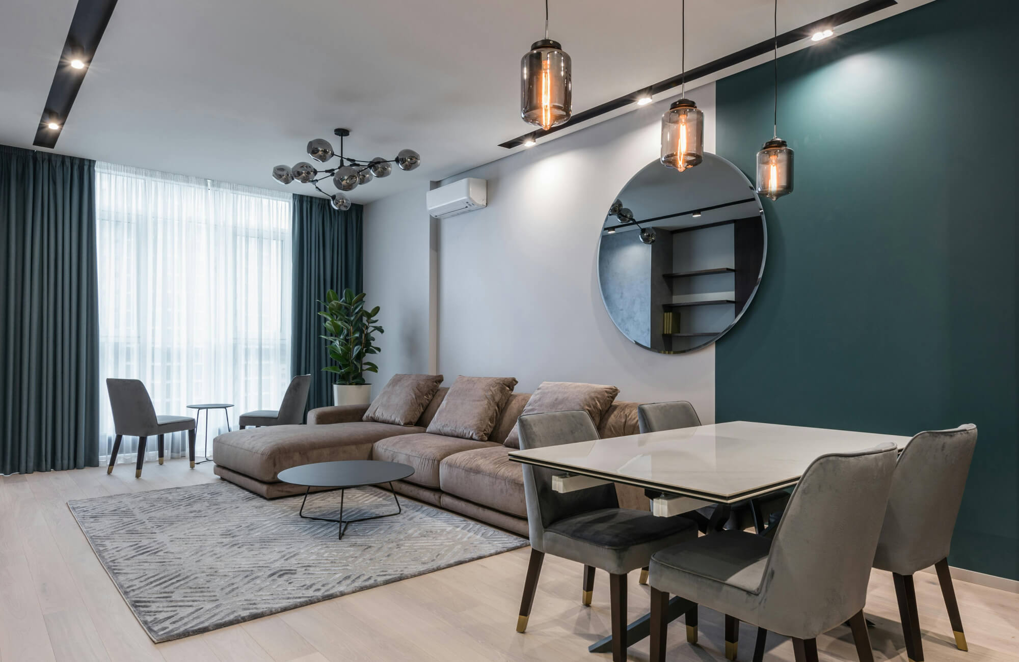null Large circular mirror mounted on a long living room wall to add light, symmetry, and depth to an open space.