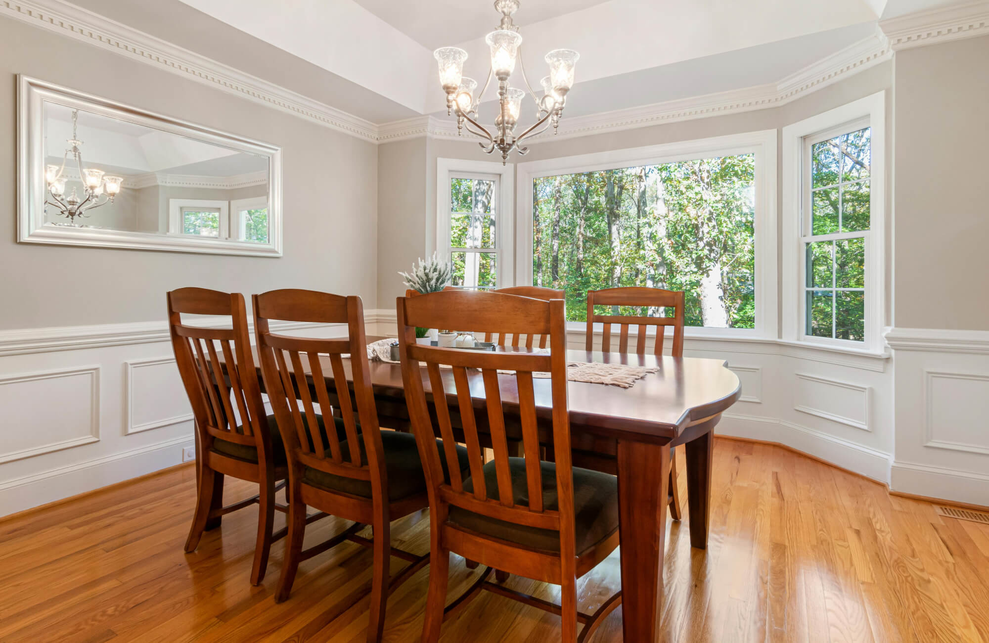 null Horizontal mirror centered behind dining table, anchoring the space and enhancing symmetry and lighting.