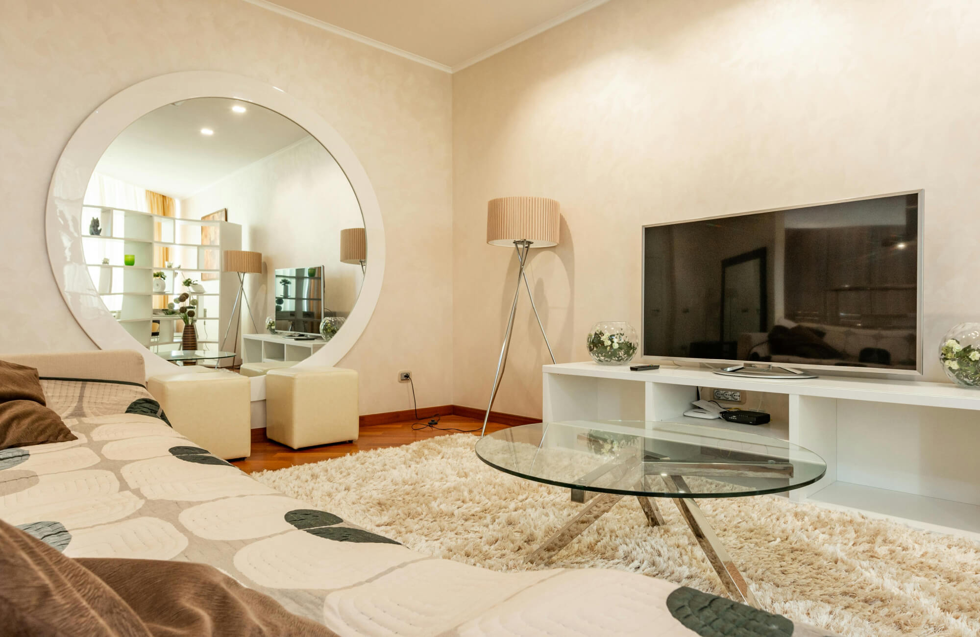 Oversized round mirror mounted on a wall near the TV stand, reflecting the seating and decor in the room.