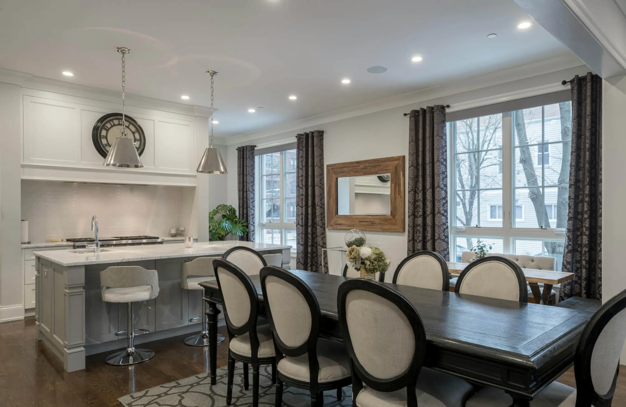 Dining room mirror placed beside the table reflecting light and seating, creating balance and visual openness in a modern layout.