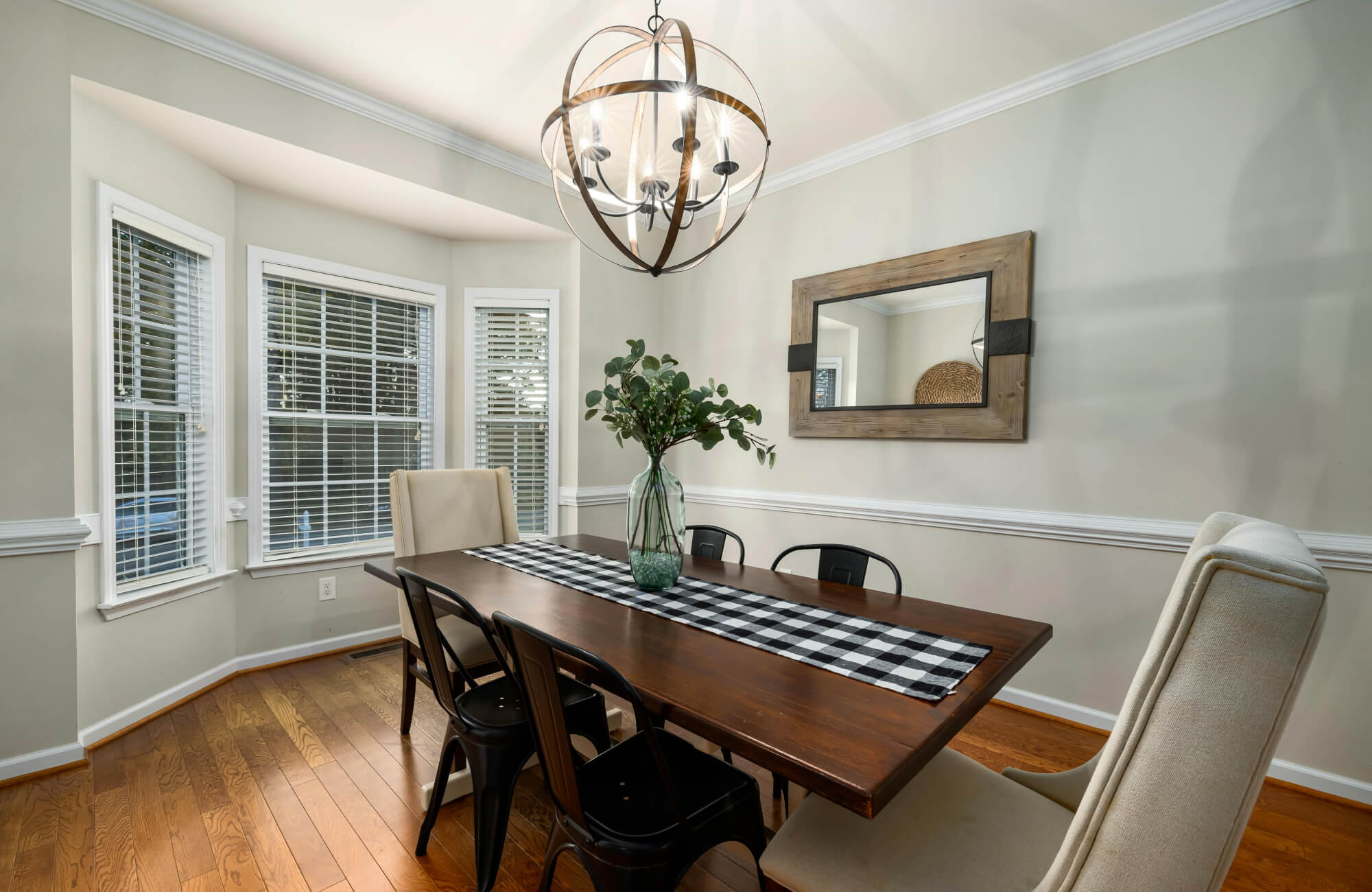null Wall-mounted mirror in a dining room reflecting the table and natural light, enhancing brightness and a sense of calm.