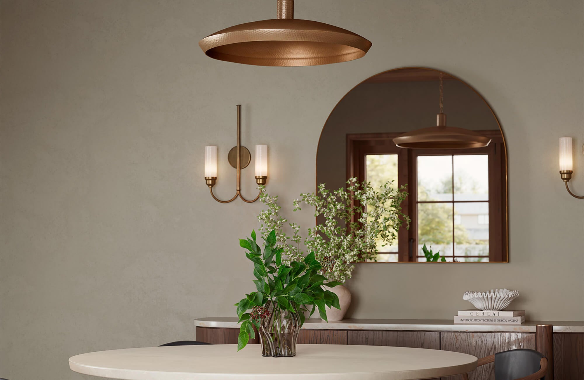 Arch mirror above dining sideboard reflecting round table and pendant light