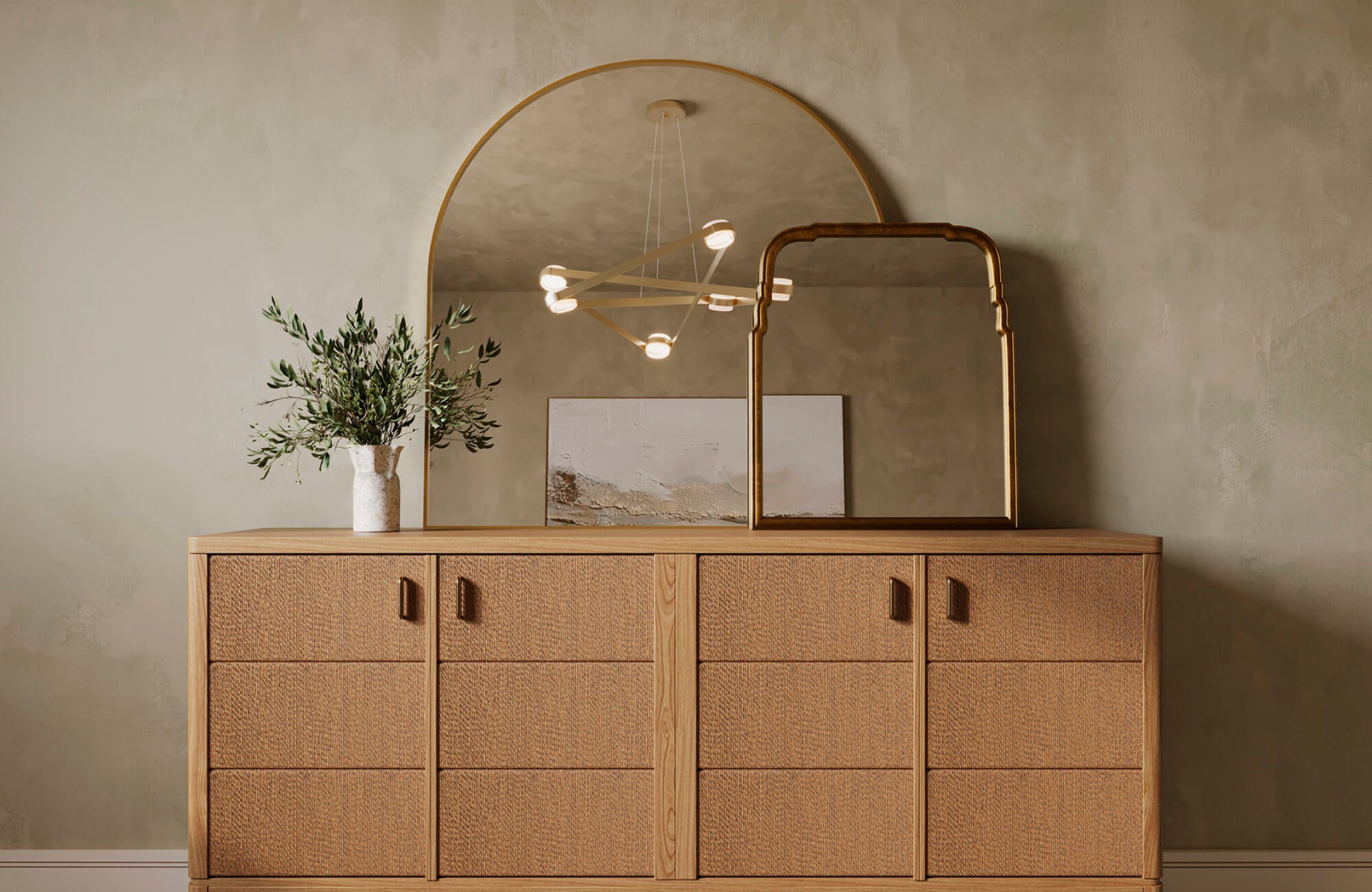 Wide arch mirror styled on a console table, reflecting a modern chandelier overhead