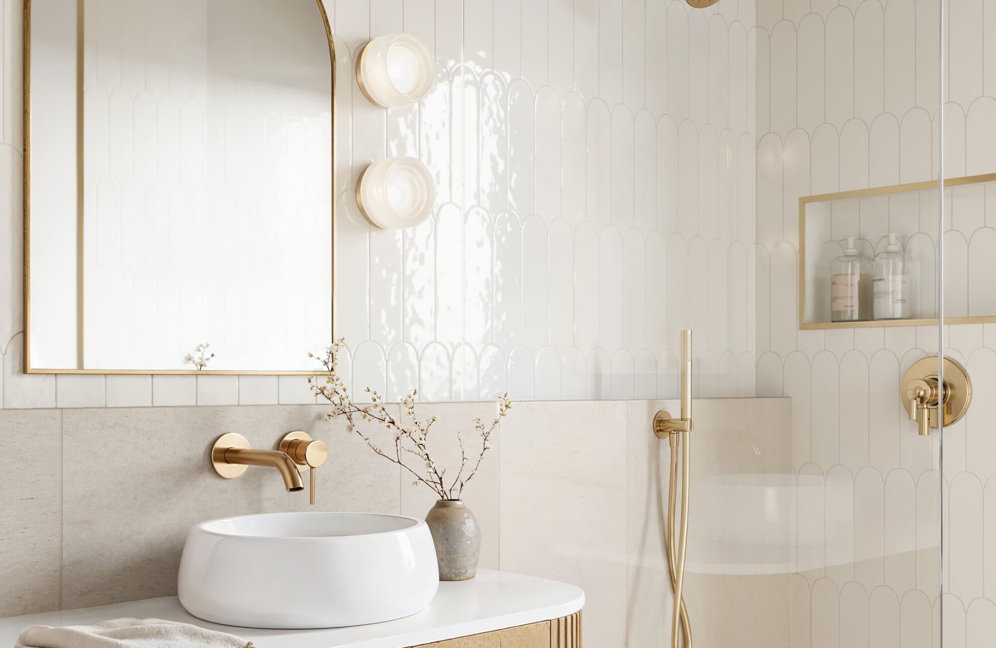 null Bright and elegant bathroom featuring white scalloped wall tiles, gold fixtures, and a sleek countertop basin under a large arched mirror.