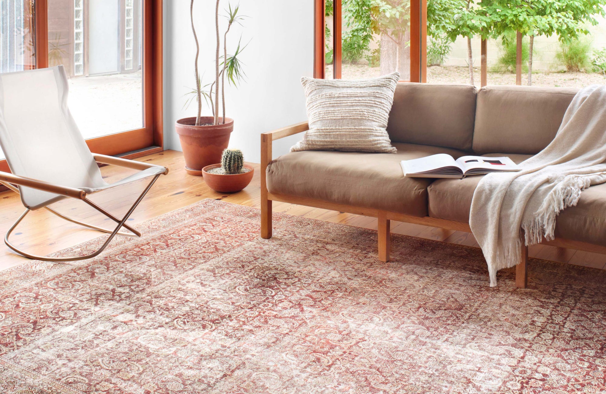 Bright, airy living space with a warm-toned vintage polyester rug, wooden-framed sofa, and natural accents, creating a relaxed, modern aesthetic.