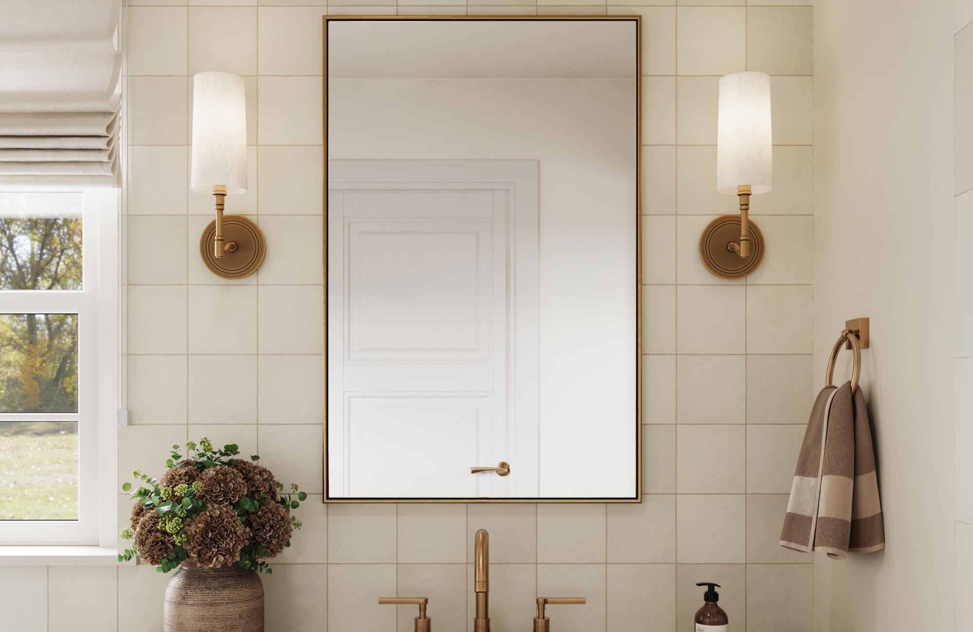 null Elegant bathroom featuring a thin-framed rectangular mirror, cream square tiles, and warm brass fixtures with twin sconces.