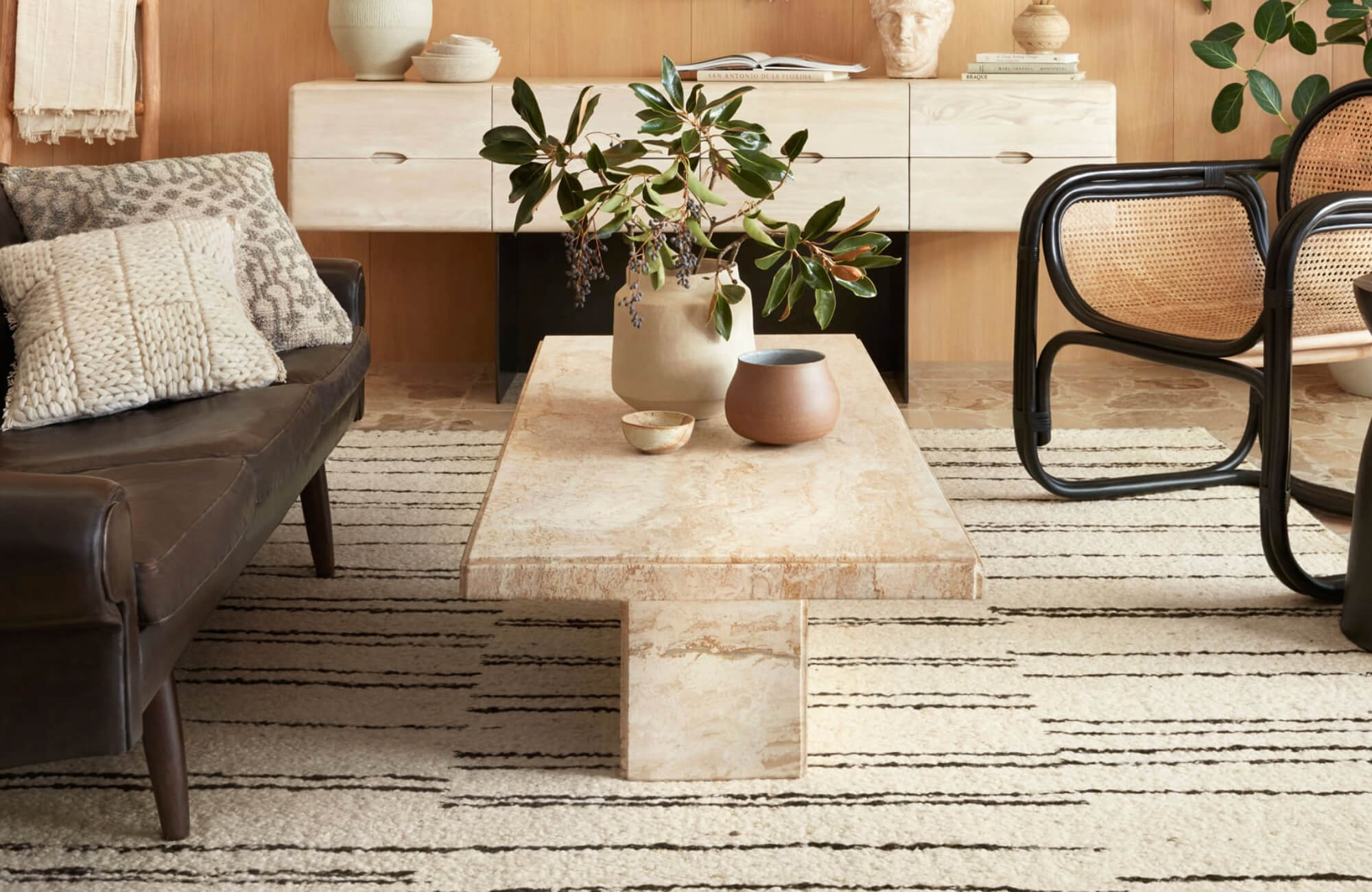 Modern interior featuring a textured wool rug with linear patterns, paired with earthy furnishings and warm wood accents for a grounded, organic feel.