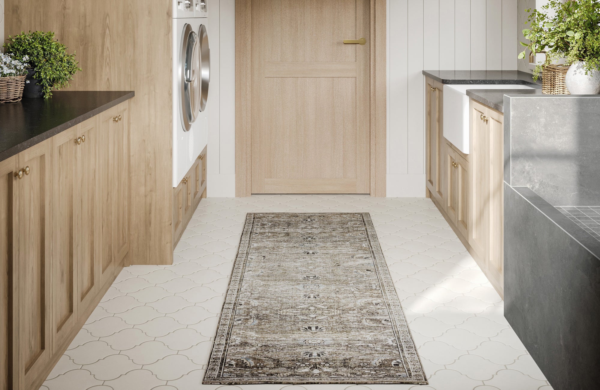 Runner rug with faded ornamental detailing adds warmth to a light-filled laundry space with wood cabinets, white walls, and patterned porcelain flooring.