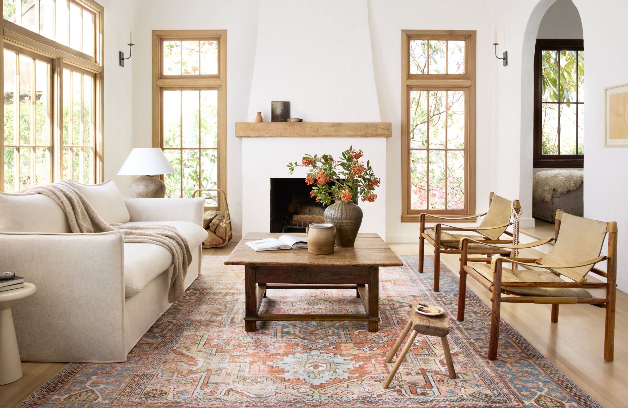 Cozy living room with white sofa and fireplace, rug positioned lengthwise beneath sofa and accent chairs for balance.