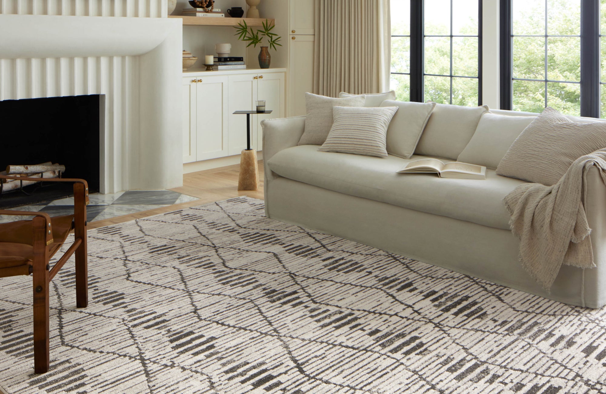 Light, airy space with large windows and modern rug placed parallel to the incoming light for enhanced brightness.