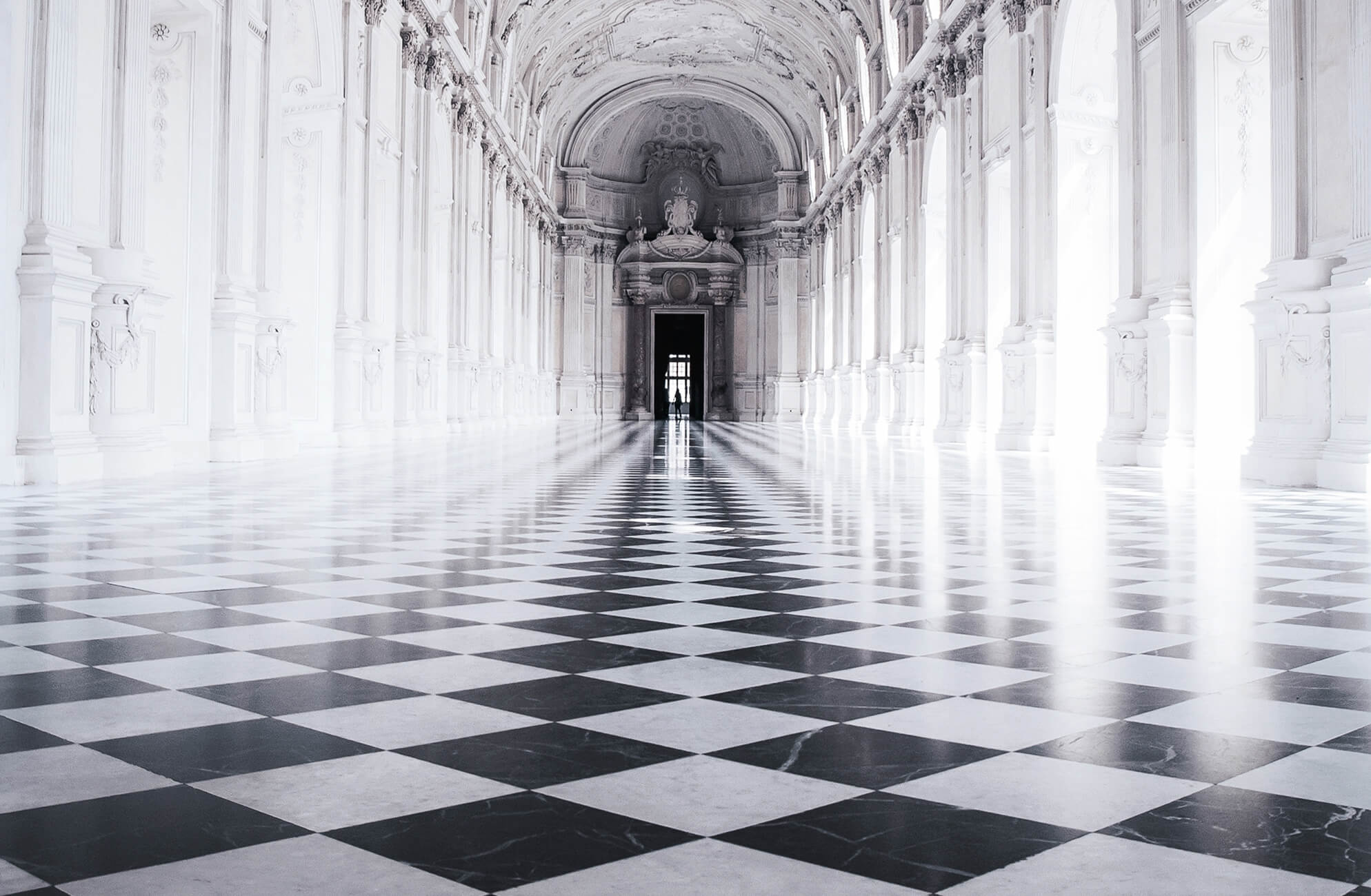 null Grand neoclassical hall featuring a vast expanse of black and white checkered marble flooring, where towering archways and ornate columns create a dramatic sense of depth, symmetry, and timeless elegance.