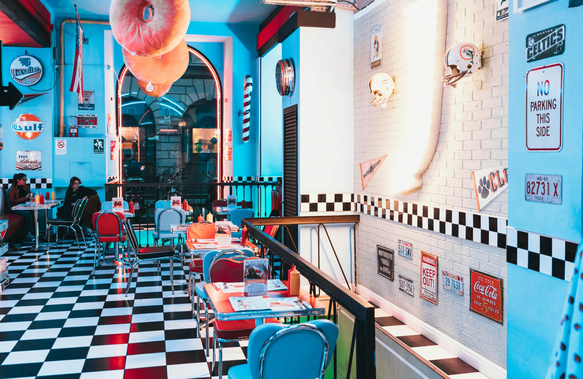 null Retro American diner interior with neon lights, chrome chairs, and black and white checkered floor tiles creating a vibrant vintage atmosphere.
