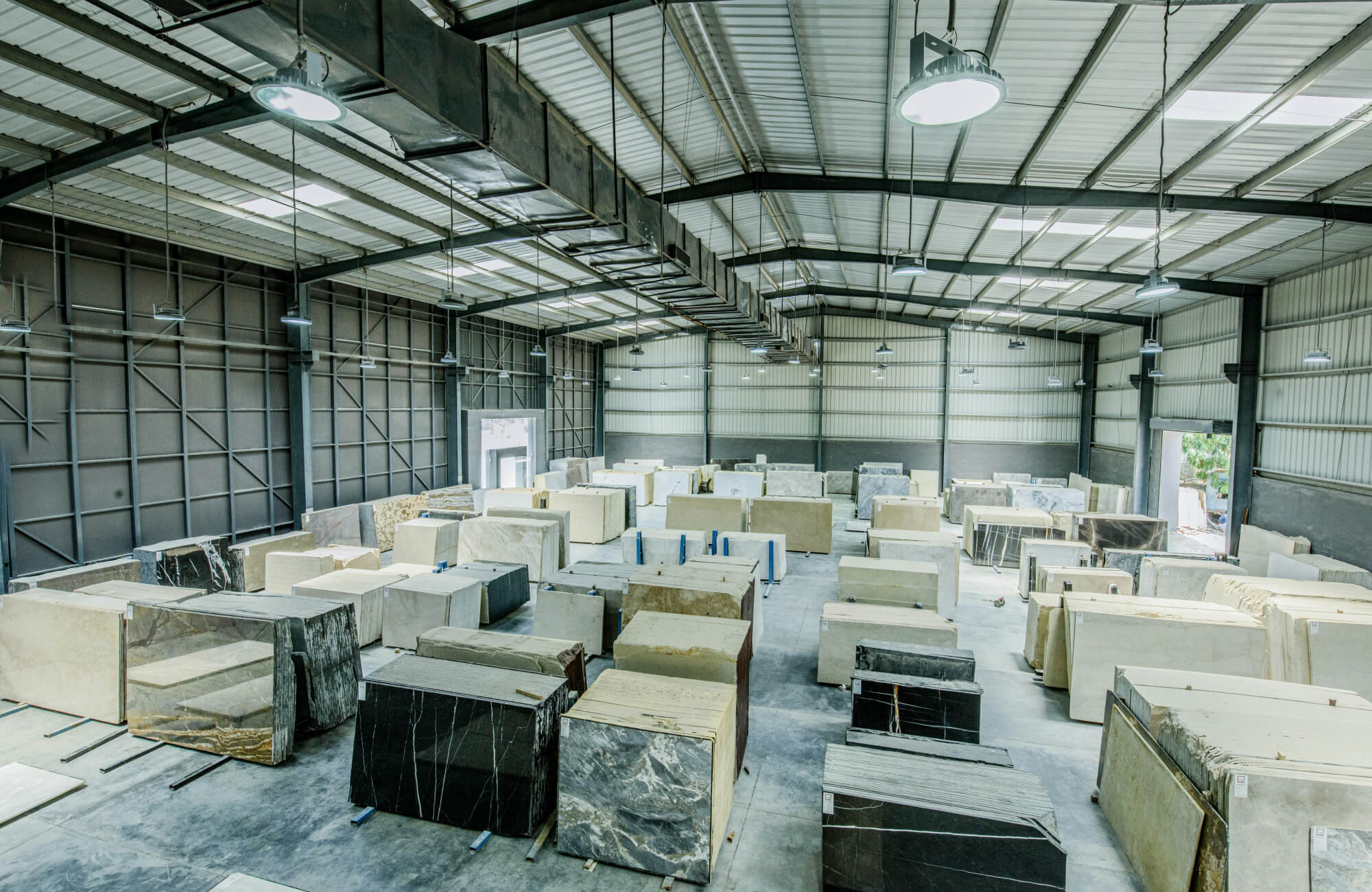 null Indoor stone warehouse displaying massive marble slabs arranged in rows under industrial lighting.