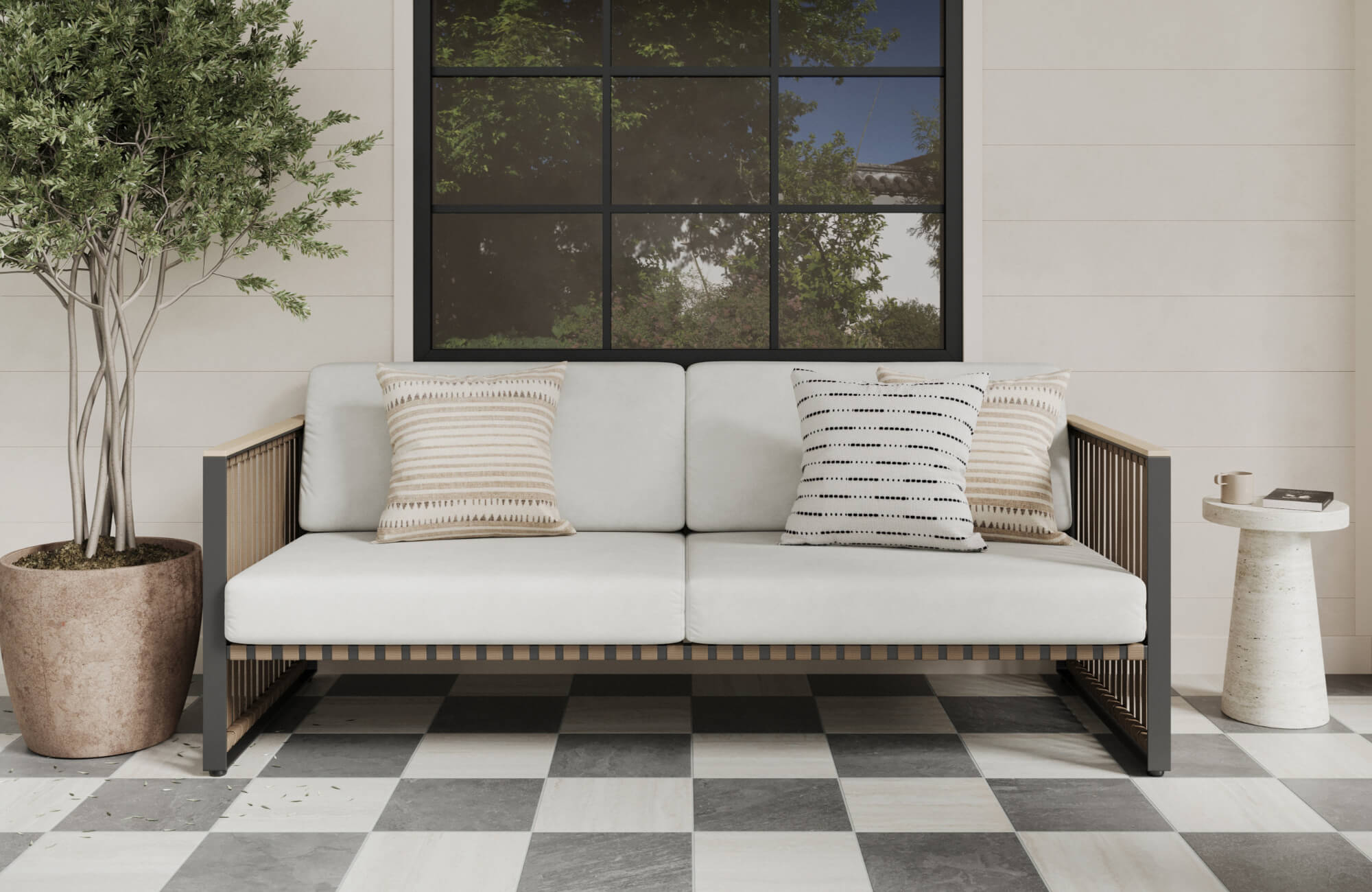 Modern patio scene with a white cushioned sofa, neutral accent pillows, and black-and-white checkerboard pavers beneath a large window.