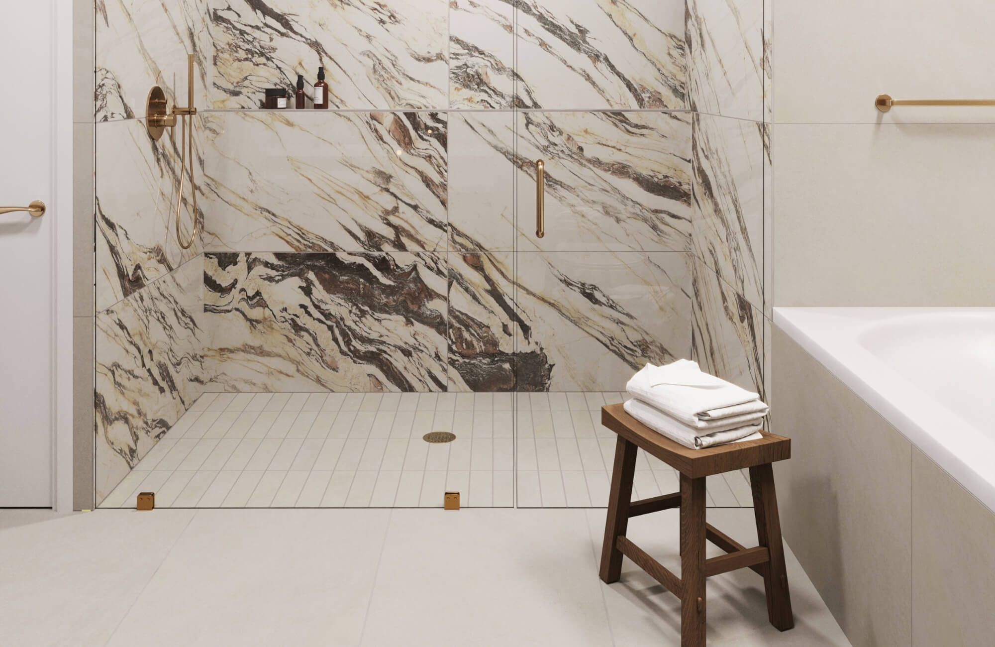 Walk-in shower with large white marble look tiles, bold black and warm gold veining, brass fixtures, a glass enclosure, and a wood stool stacked with towels.