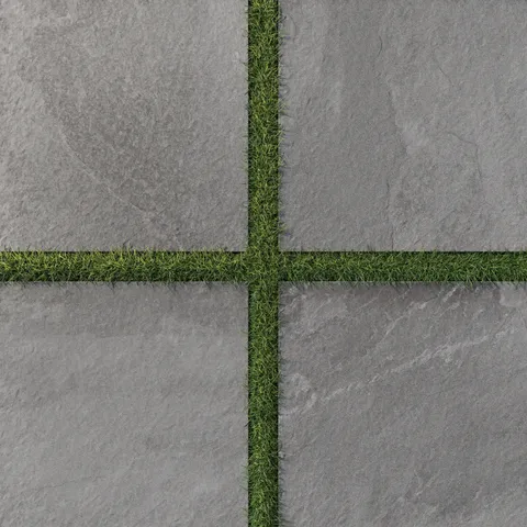 Bowden 24x24 Grip Porcelain 2CM Paver in Graphite, showcasing deep gray tones with lush grass accents for a refined outdoor aesthetic.