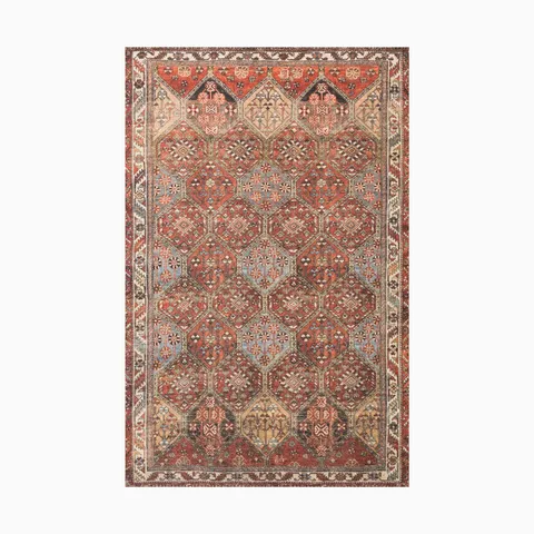 Power-loomed polyester rug with a rust base and multi-tonal accents, featuring a traditional geometric motif with intricate detailing.