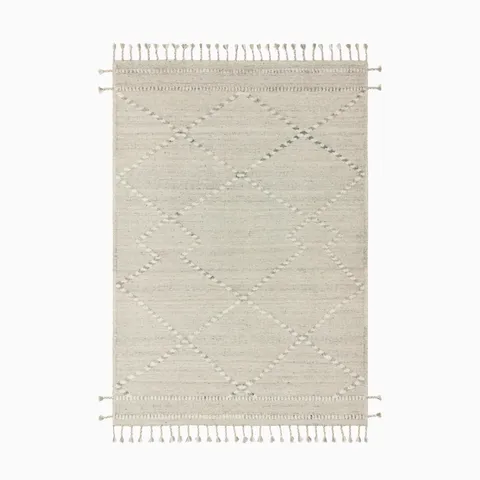 Hand-knotted rug crafted from a blend of wool, cotton, polyester, and rayon in cream and dove, featuring a subtle geometric pattern and tasseled edges for a contemporary finish.
