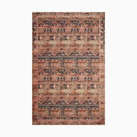 Traditional power loomed rug made of polyester with an intricate tribal-inspired pattern in rich red, navy, and beige tones, evoking a warm, vintage charm.