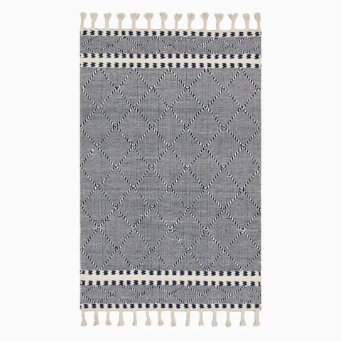 Boho-inspired hand loomed wool area rug with a navy and white geometric diamond pattern and tassel fringe, blending style and texture.