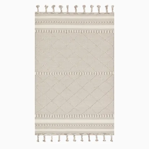 Hand loomed beige wool rug featuring a delicate diamond pattern, subtle woven details, and decorative fringe.