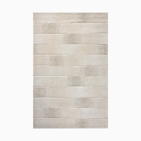 Power loomed area rug from Egypt made of polypropylene with a subtle linear pattern in soft beige and cream tones.