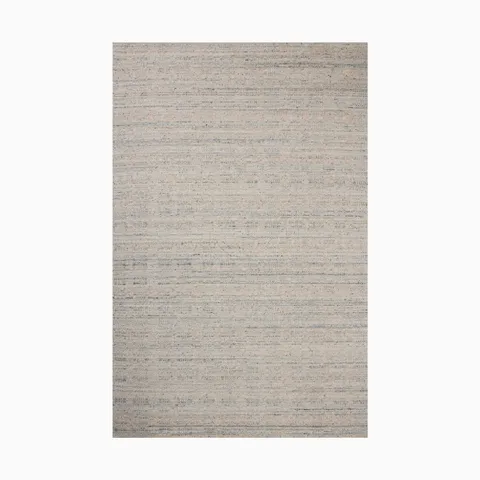 Soft beige hand loomed rug made of nylon and wool with subtle blue-gray undertones and a woven fabric-like texture, perfect for a serene, organic aesthetic.