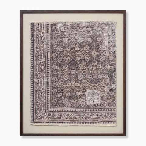 Framed textile wall art with faded geometric motifs, ornate borders, and softly frayed edges in muted beige and dark gray tones.