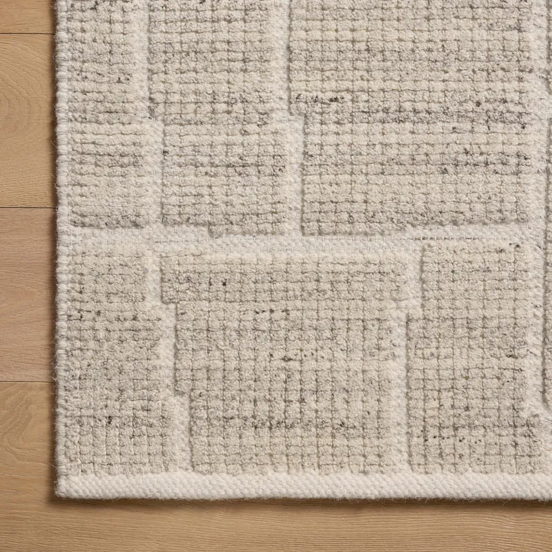 This close-up highlights a grayish beige rug crafted from a GoodWeave-certified wool-cotton blend, with abstract rectangular lines emerging through a tightened, flattened weave.