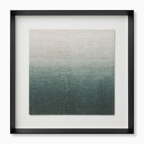 Framed textile artwork with a soft gradient from pale neutral tones into deeper, greenish blue shades, housed in a black shadowbox frame for a modern, tactile accent.
