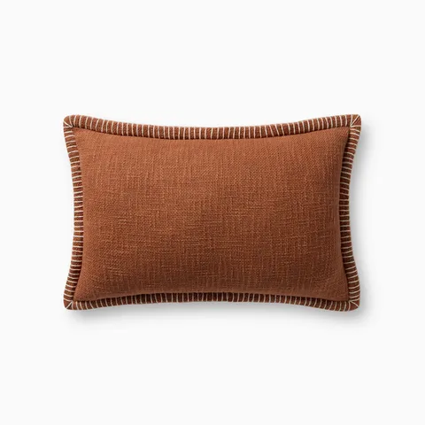Polyester pillow in a warm terracotta tone, sized 13” x 21”, with a woven texture, white whipstitching, and an antique bronze zipper concealed by a tailored flap.