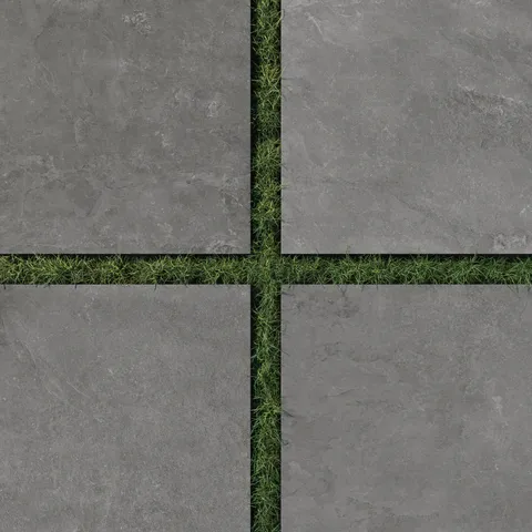 Sleek Wren 24x24 charcoal-gray porcelain pavers with a 2cm outdoor matte finish, spaced over lush green grass for a bold and modern outdoor design.