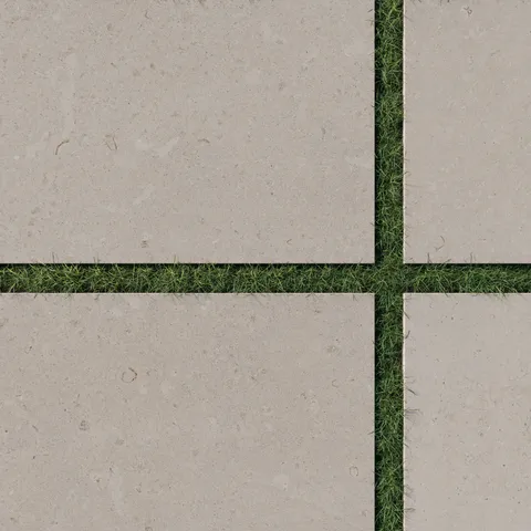 Close-up of Wren 24x36 grip porcelain 2cm paver tiles in dune, showcasing a natural beige tone with precise placement on lush green grass for modern outdoor designs.