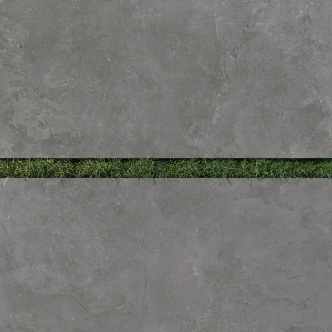 Detailed view of Wren 24x48 2cm matte charcoal tiles with a sleek dark gray finish, paired with vibrant green grass for a striking outdoor contrast.
