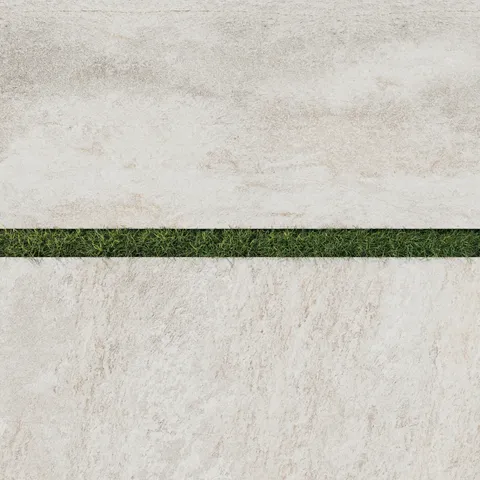 Close-up of Carter Stone 24x48 Matte Porcelain Pavers, 2cm thick, featuring a subtle beige stone-like texture with grass inlays.