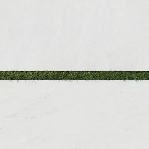 Close-up of Carter Ash 24x48 Matte Porcelain Pavers, 2cm thick, showcasing a sleek white surface paired with vibrant green grass for outdoor elegance.