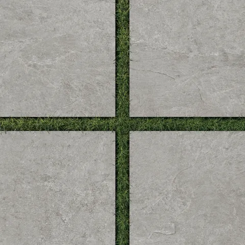 Dawson 24x24 Grip Porcelain 2cm Paver Tile in Ash, arranged with green grass joints, highlighting its natural stone texture for outdoor spaces.